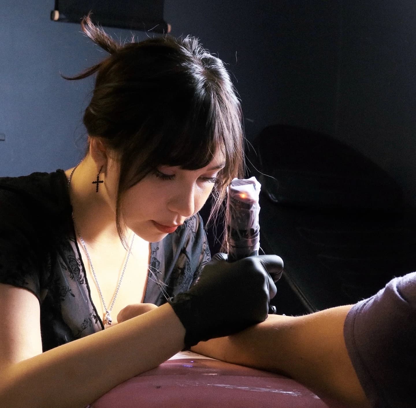 Javiera, tatuadora de Cazagemas, concentrada tatuando un antebrazo en el estudio